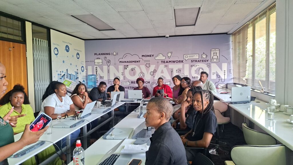 Entrepreneurs working on laptops during a workshop in front of the Softstart BTI innovation wall
